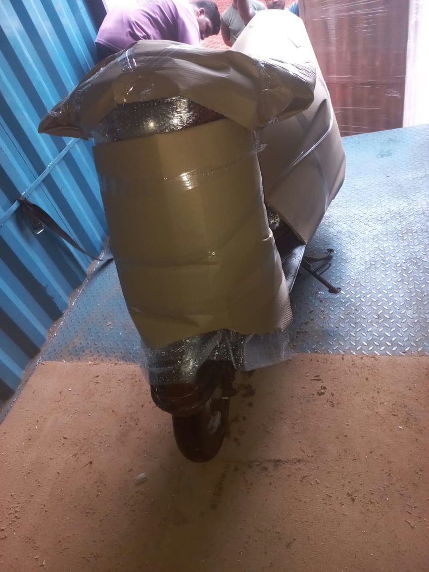 Thorough multi-layer wrapping of a scooter with cardboard and protective film for safe transit.
