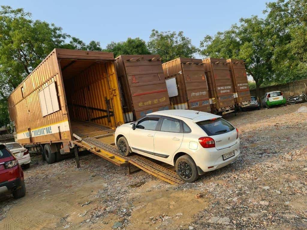 Modern car transport service: a white hatchback being carefully driven onto a specialized loading ramp.