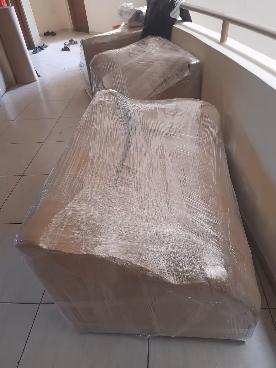Carefully wrapped armchairs staged in a hallway, ready for the move.