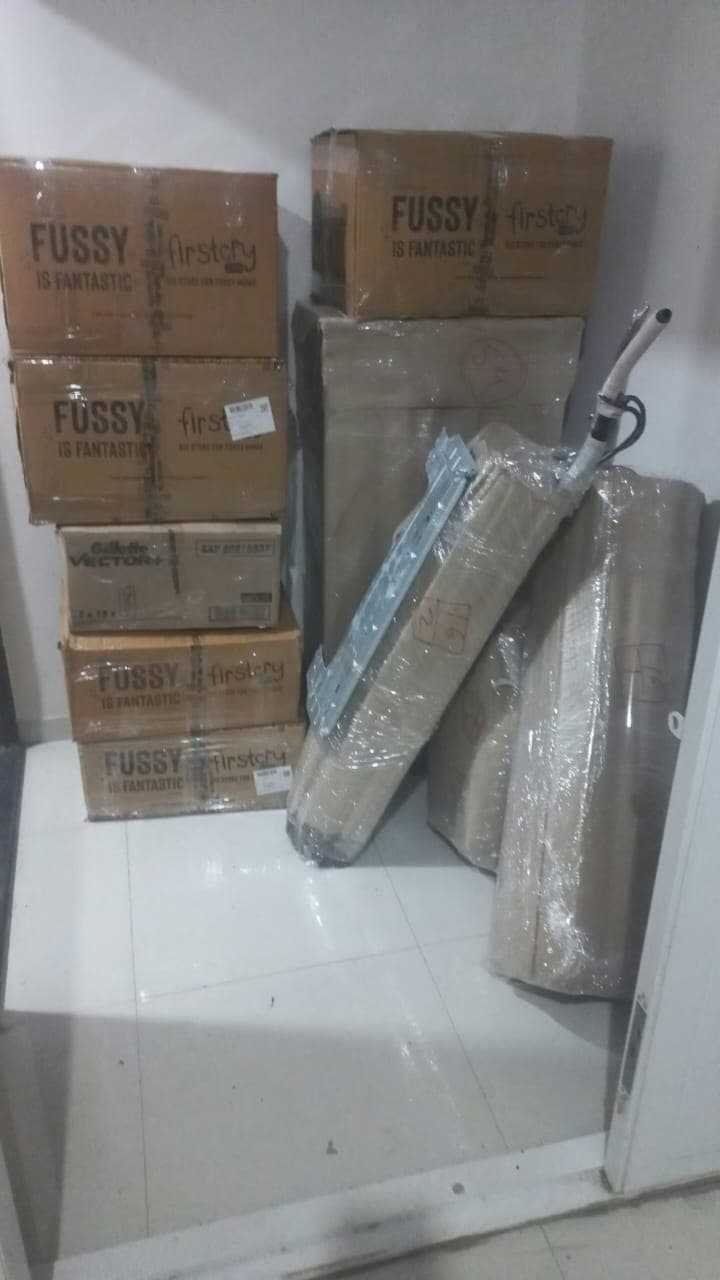 Securely packed household goods and branded boxes organized against a wall, ready for moving.