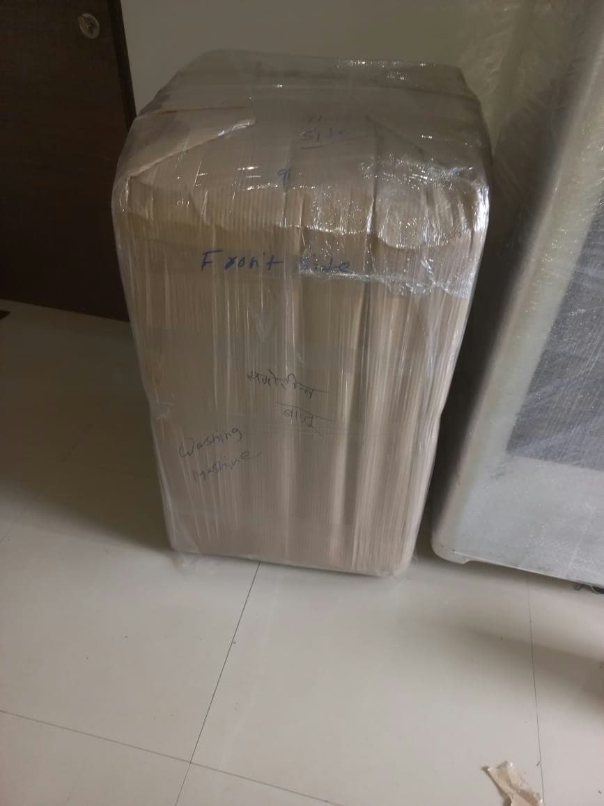 A washing machine professionally packed with cardboard and film, and clearly labeled for proper handling.