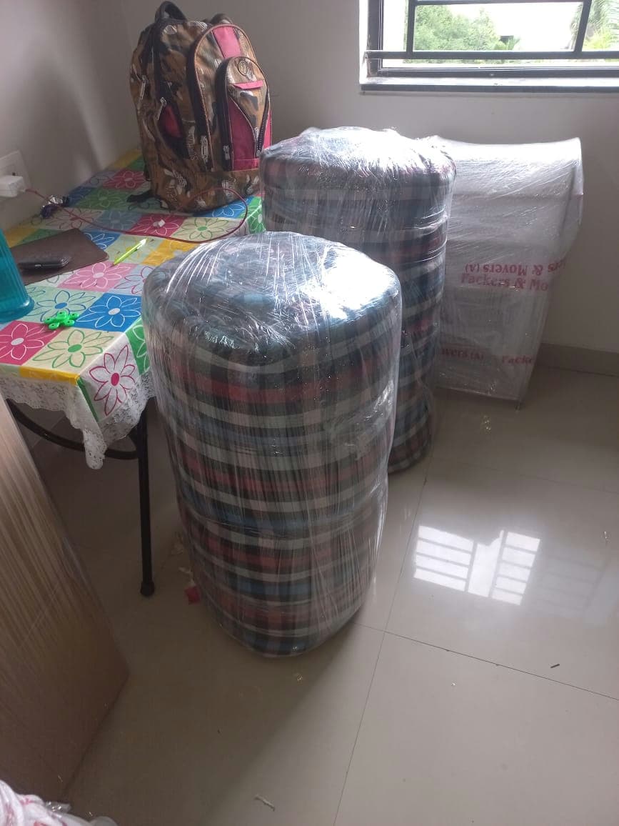 Rolled and plastic-wrapped mattresses for hygienic, secure, and compact transport during a home move.