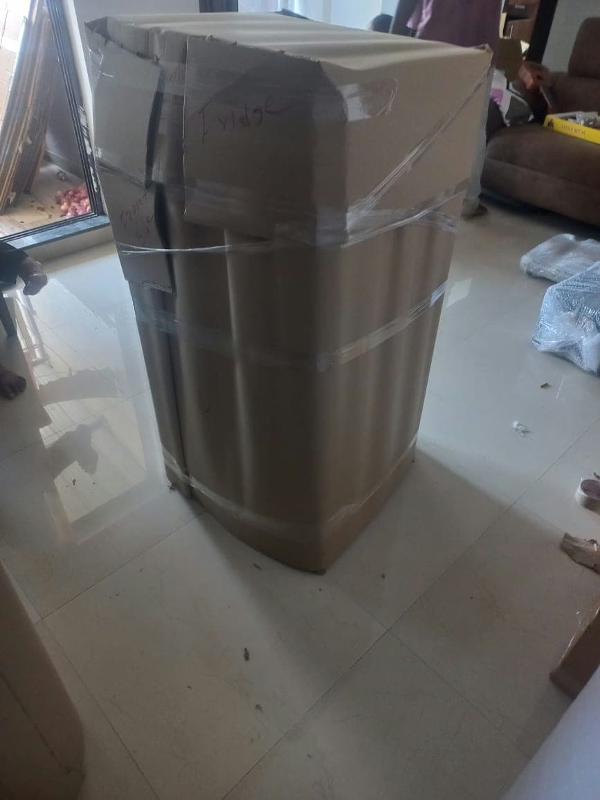 A refrigerator professionally encased in thick corrugated cardboard for maximum protection during transit.