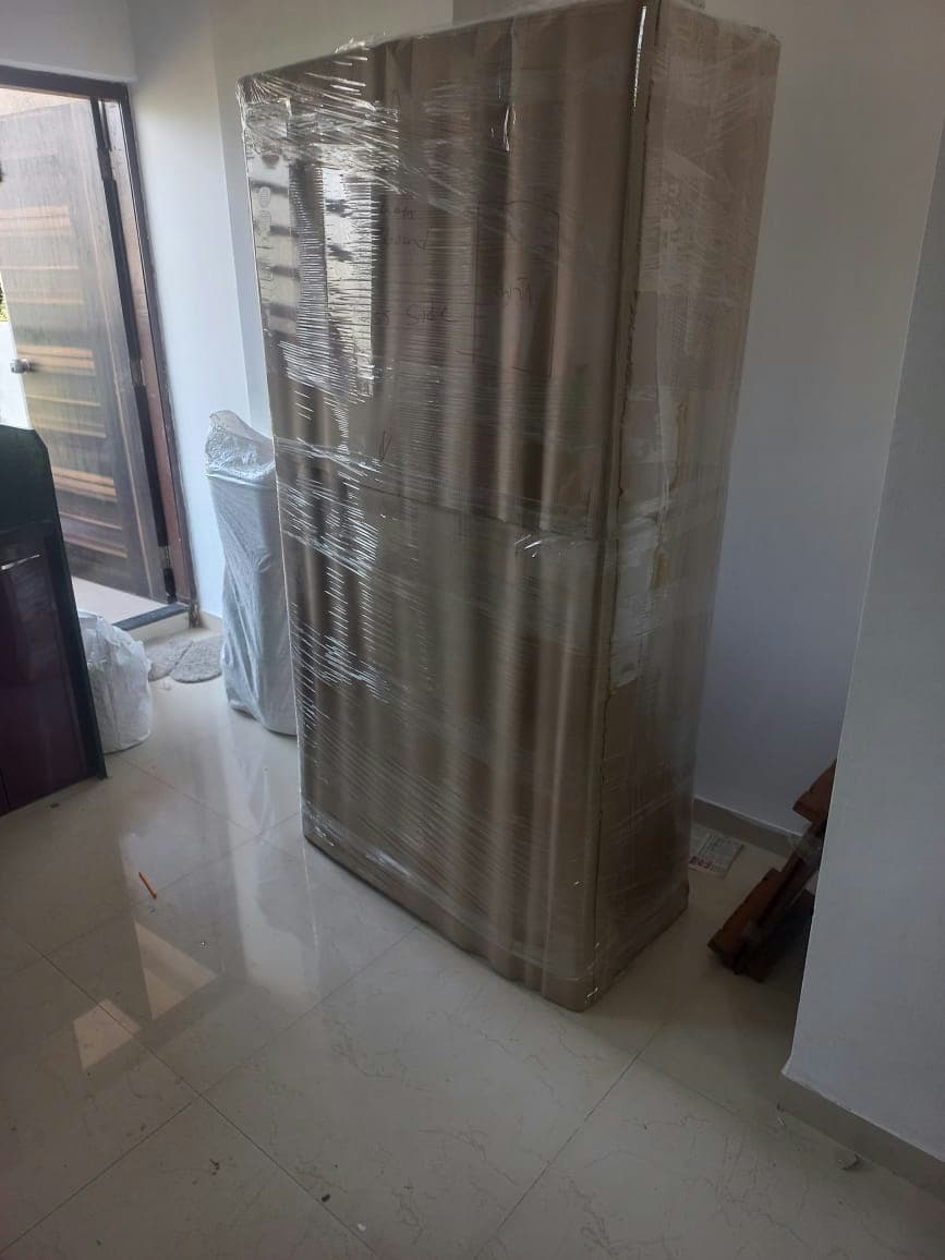 A large wardrobe, fully wrapped and protected, standing ready to be moved from the home.