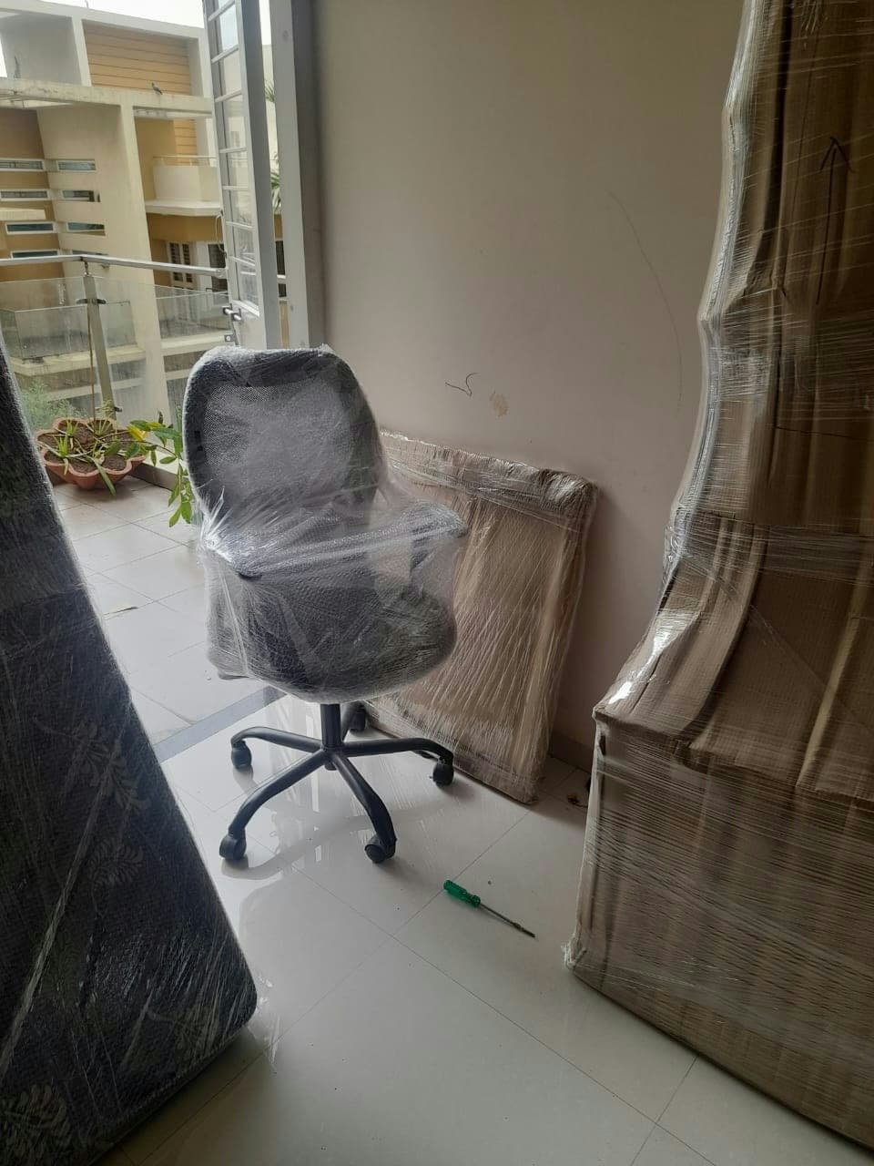 Office chair and furniture panels expertly wrapped and staged for moving from an apartment.