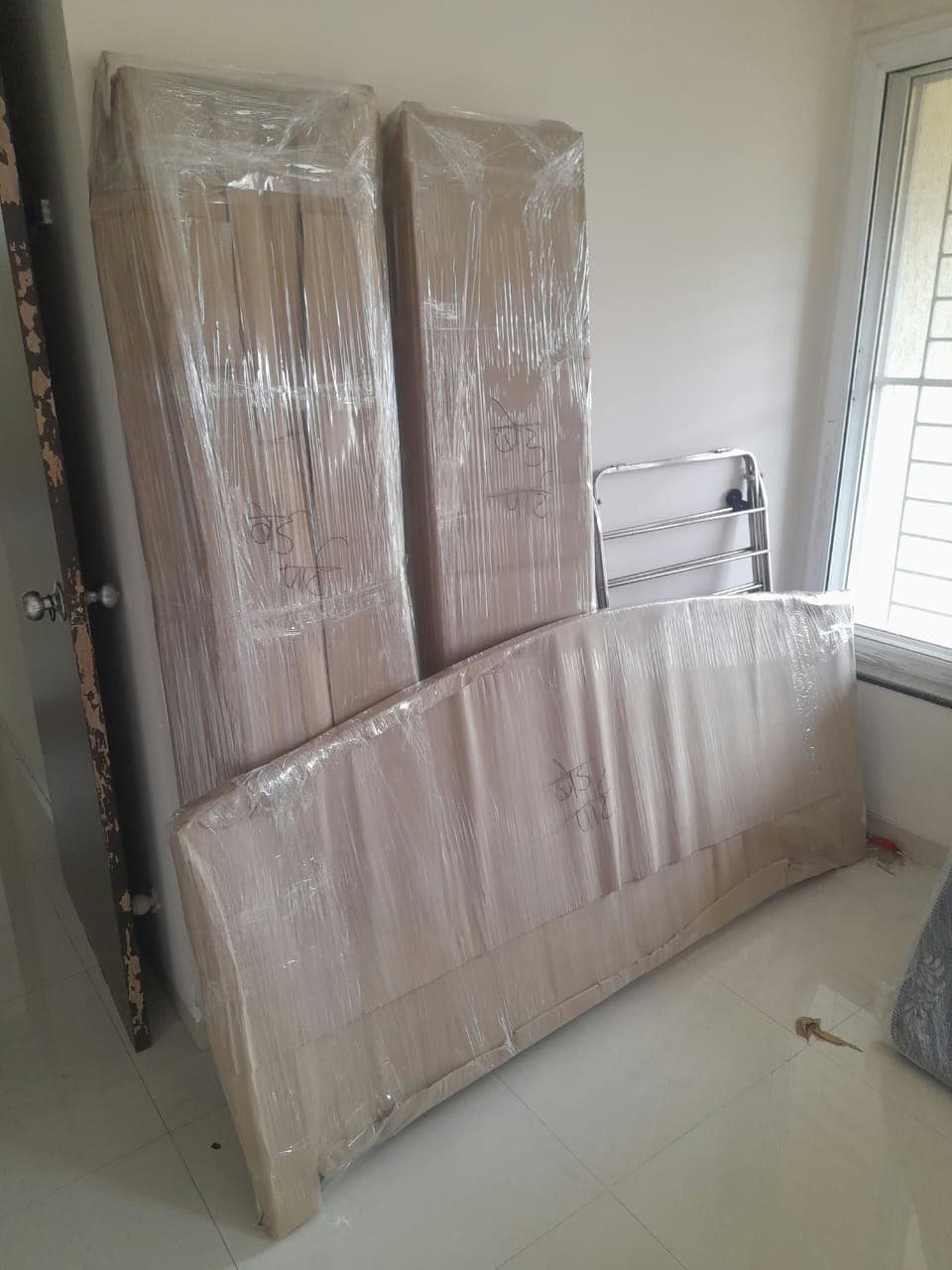 Dismantled bed components, including headboard and frame, professionally wrapped for safe relocation.