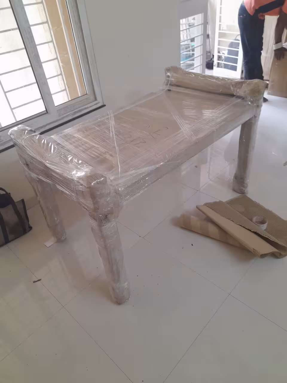 Multi-layer protection for a wooden table using paper and plastic wrap.