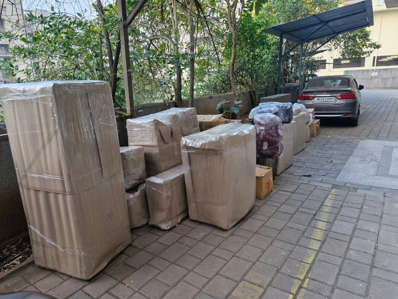 All household goods, from large furniture to small boxes, securely packed and awaiting transport in a driveway.